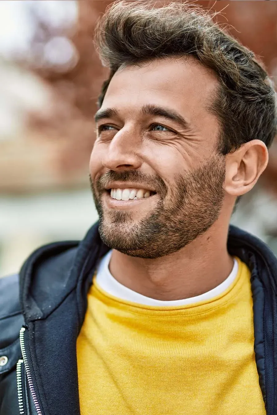 A man smiling outdoors in warm light.