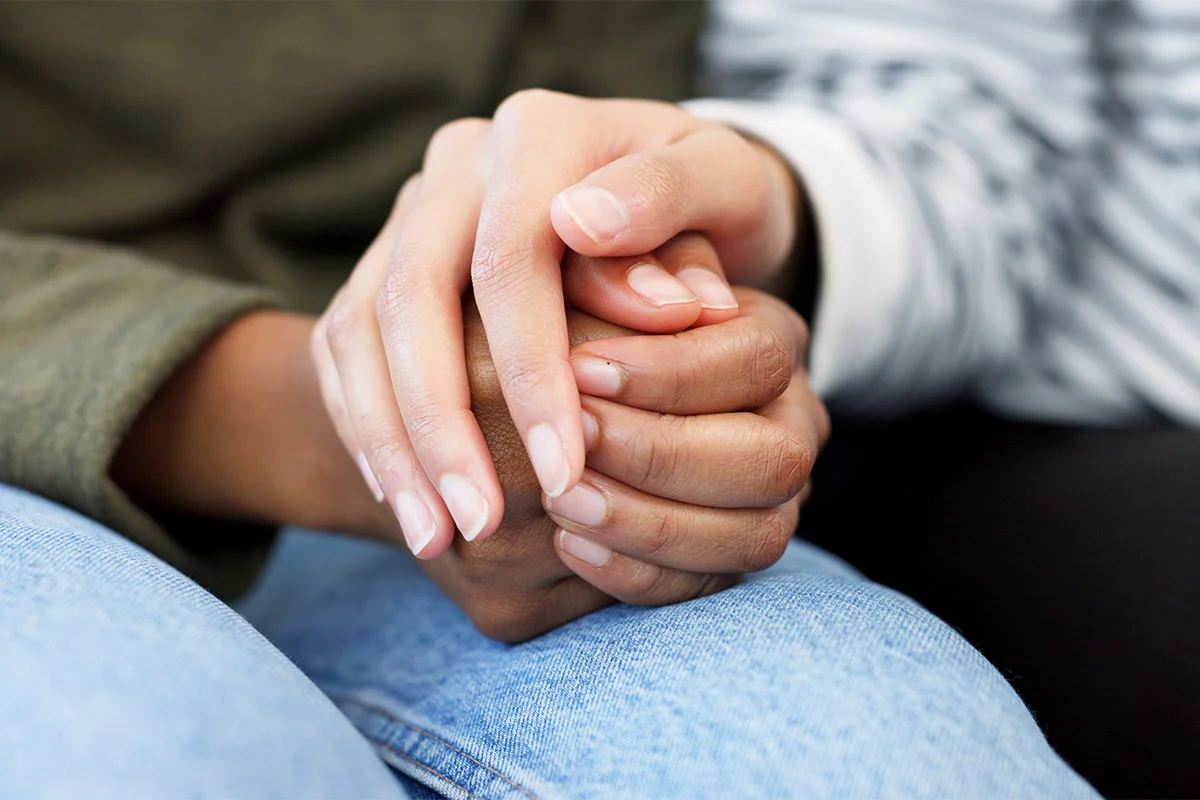Comforting hands of a person in a striped shirt during treatment